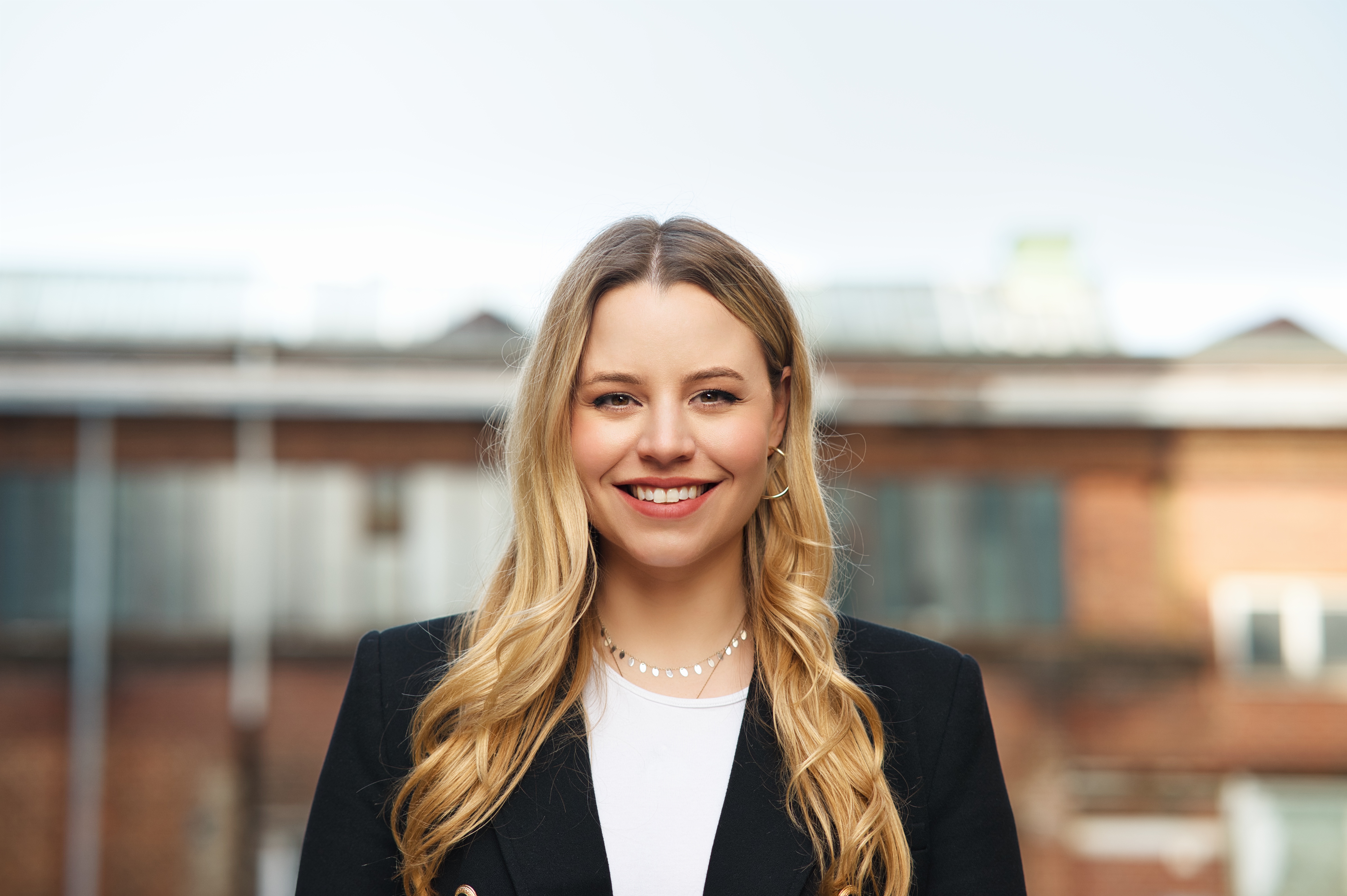 Professional female lawyer Melissa Nagel in modern office, smiling warmly, business portrait, approachable and trustworthy, natural lighting, professional attire